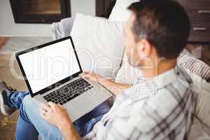 Man using laptop while sitting on sofa at home