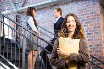 Businesswoman standing near staircase with documents