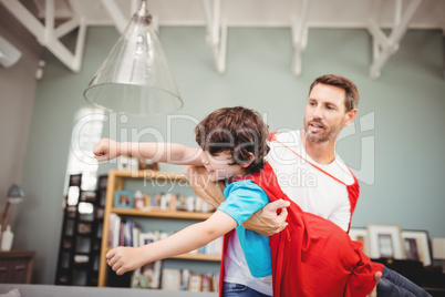 Father carrying son wearing superhero costume