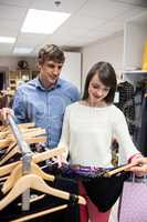 Couple selecting a dress while shopping for clothes