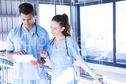 Doctors using digital tablet in corridor