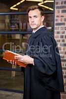 Lawyer standing near library with law book