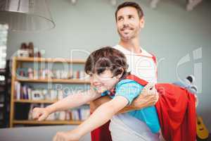Father carrying son with superhero costume