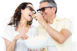 Smiling couple with 3D glasses eating popcorn