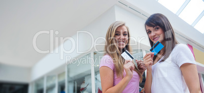 Portrait of happy women showing their credit cards in mall