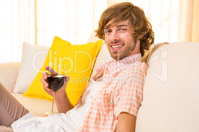 Handsome man enjoying a glass of wine on the couch