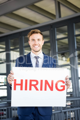 Businessman holding a hiring signboard