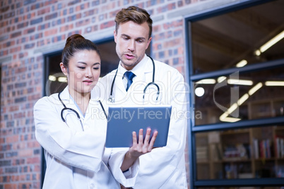 Doctors discussing over digital tablet near library