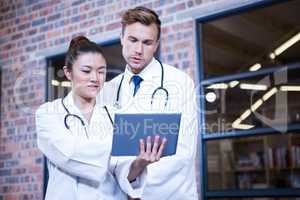 Doctors discussing over digital tablet near library