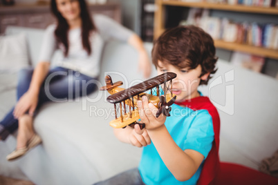 Boy wearing superhero costume while holding airplane