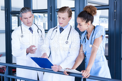 Doctors discussing medical report in corridor