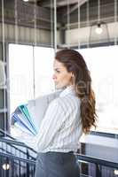 Busy businesswoman carrying folders with files documents
