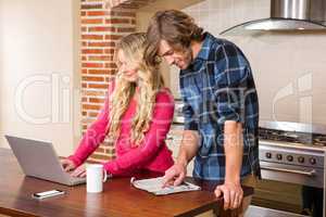 Cute couple using laptop and reading newspaper