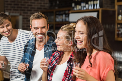 Friends laughing with shot glasses in hand