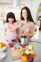 Portrait of Smiling mother and daughter preparing fruit juice