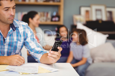 Close-up of man using mobile phone while family in background