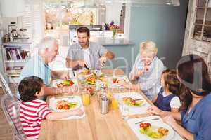 Smiling family with grandparents discussing at dining table