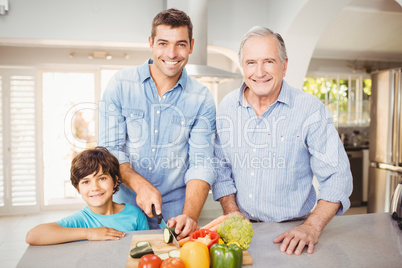 Happy man chopping vegetables with son and father