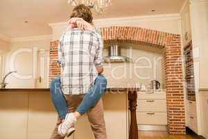 Cute couple cuddling with girlfriend sitting on the counter