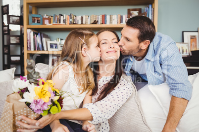 Father and daughter kissing mother