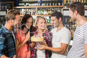 Friends in a circle holding a cake