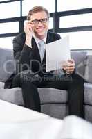 Happy young businessman holding document while sitting at sofa