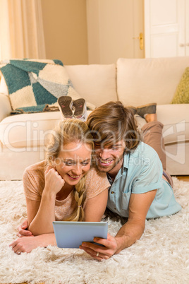 Cute couple lying on the carpet using tablet