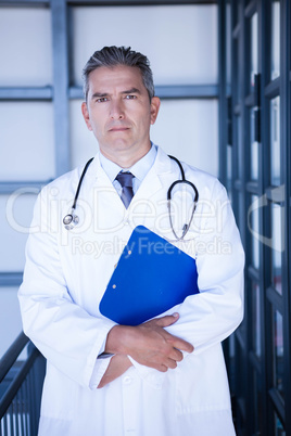 Portrait of male doctor standing with clipboard