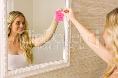 Beautiful blonde putting I love you note on mirror