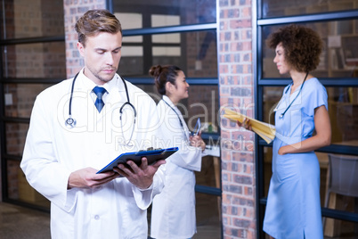 Male doctor looking at clipboard near library