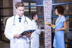 Male doctor looking at clipboard near library