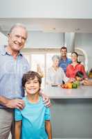 Boy with grandfather while family preparing food in background
