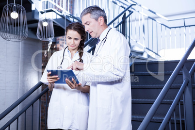 Doctors using digital tablet on staircase