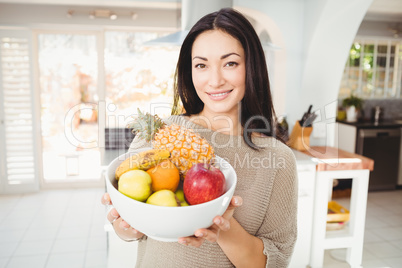 Portrait of happy woman holding fruits bowl