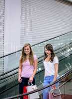 Two beautiful women on escalator of shopping mall