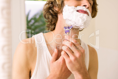 Handsome man shaving in the bathroom