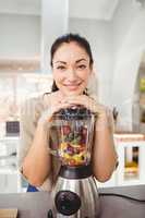 Portrait of cheerful woman preparing fruit juice
