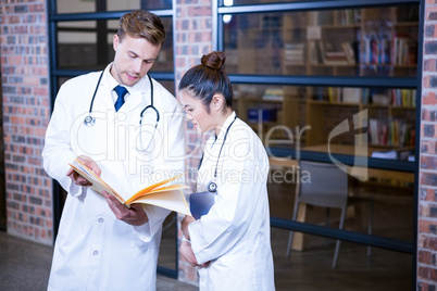 Two doctors looking at file and discussing near library