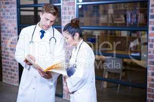 Two doctors looking at file and discussing near library