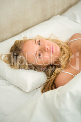 Pretty woman looking tired and lying in bed