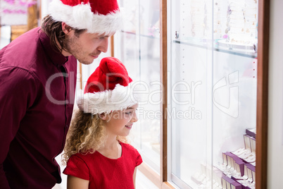 Father and daughter in Christmas attire looking at jewelry displ