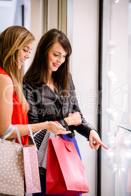 Two beautiful women talking while window shopping