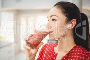 Woman drinking fruit juice while listening to music