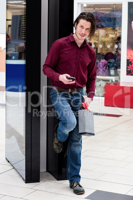 Man holding a shopping bags and using a mobile phone