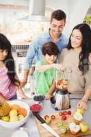 Cheerful family preparing fruit juice