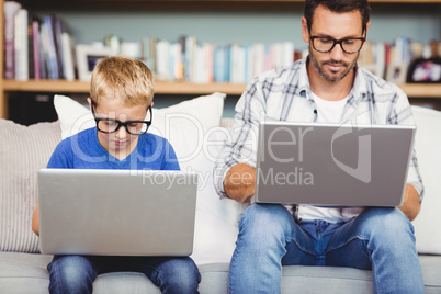 Father and son with eyeglasses working on laptop