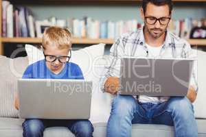 Father and son with eyeglasses working on laptop