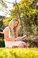 Beautiful blonde sitting on the grass reading