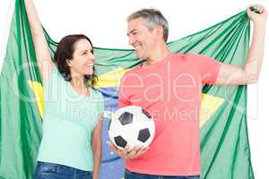 Happy couple fan of soccer holding Brazil flag