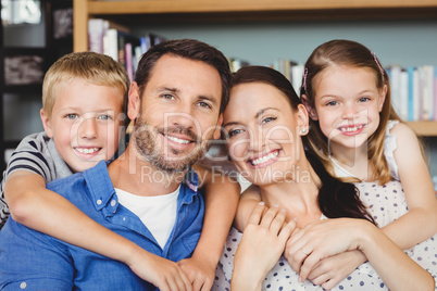 Portrait of cheerful family against shelf in living room